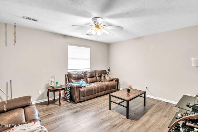 living room with ceiling fan, light hardwood / wood-style floors, and a textured ceiling