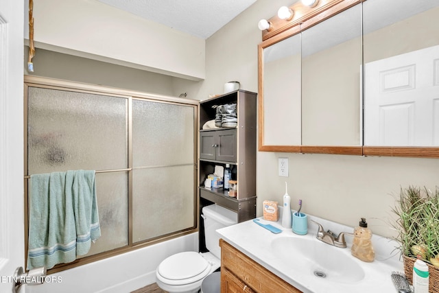 full bathroom with enclosed tub / shower combo, vanity, toilet, and a textured ceiling