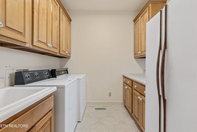 laundry area featuring cabinets, washing machine and dryer, and light tile patterned floors