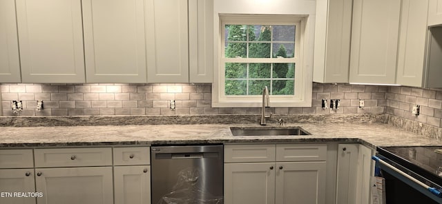 kitchen featuring sink, light stone counters, stainless steel dishwasher, decorative backsplash, and white cabinets