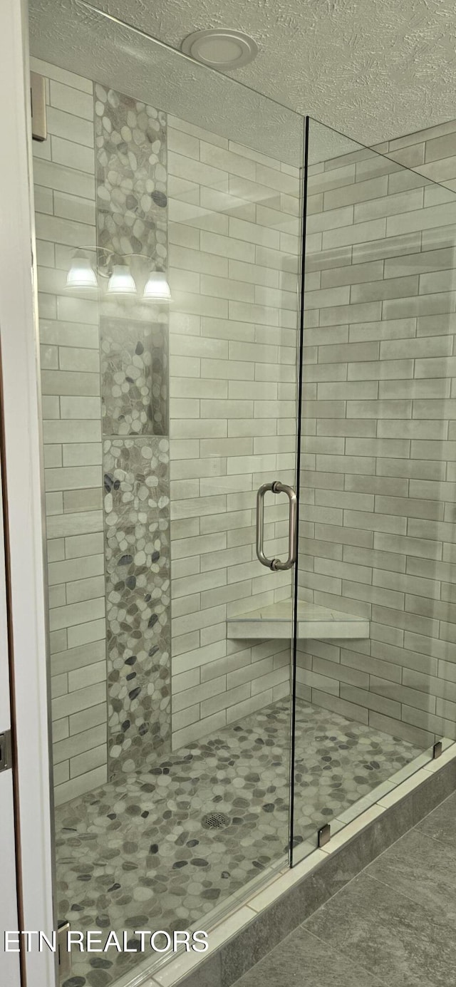 bathroom with a shower with shower door and a textured ceiling