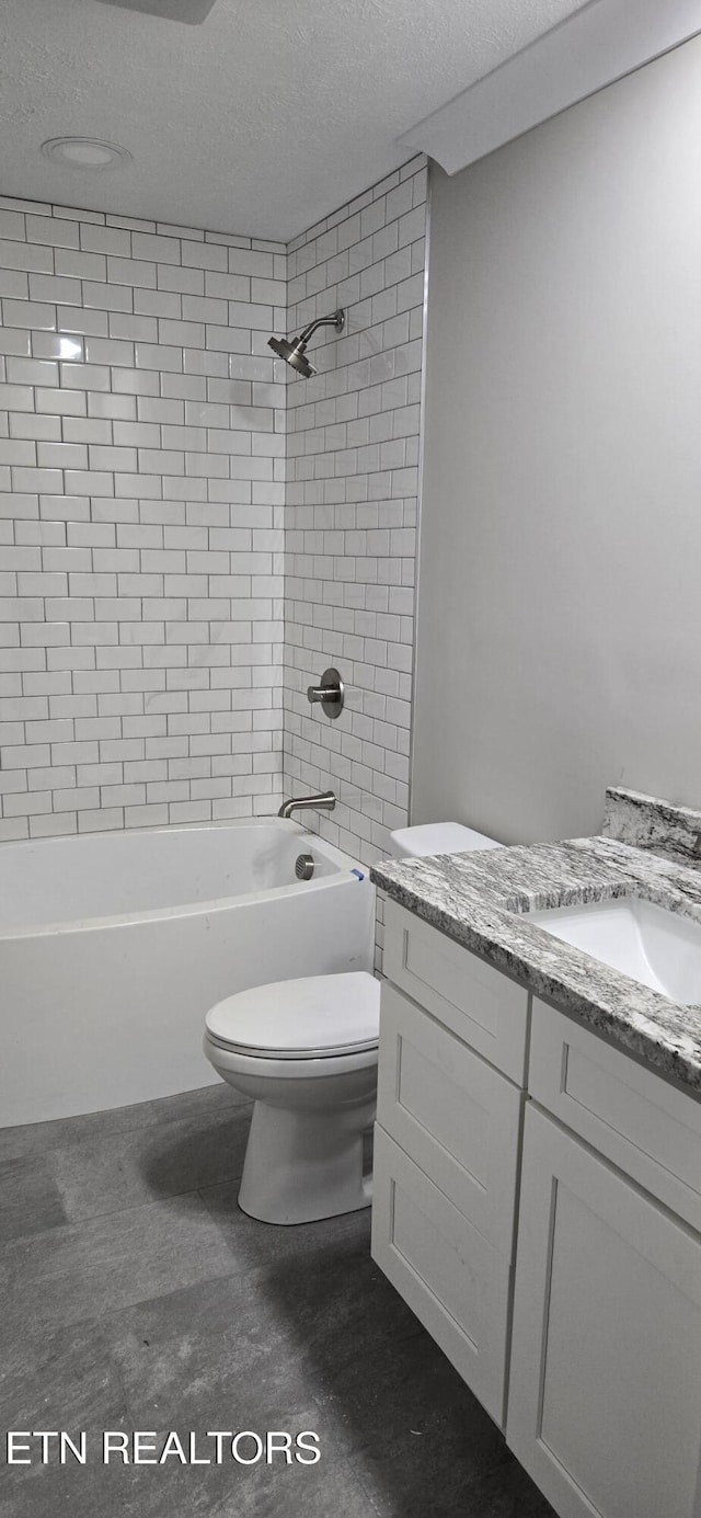 full bathroom featuring toilet, wood-type flooring, a textured ceiling, vanity, and tiled shower / bath combo