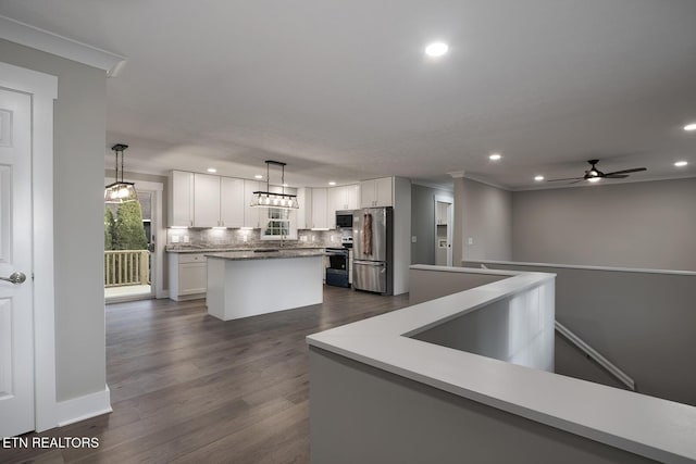 kitchen with stainless steel appliances, a kitchen island, hanging light fixtures, and white cabinets