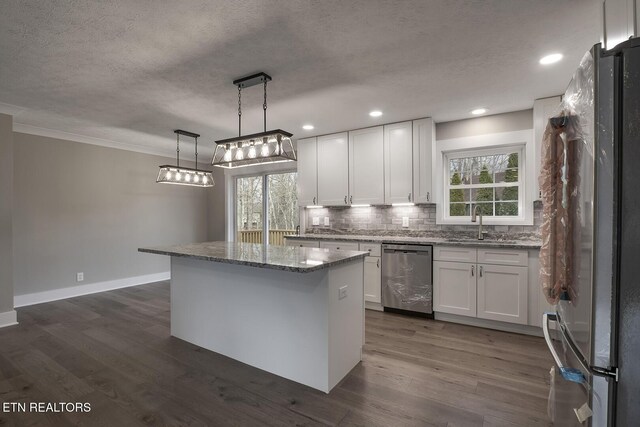 kitchen featuring appliances with stainless steel finishes, decorative light fixtures, a center island, and white cabinets