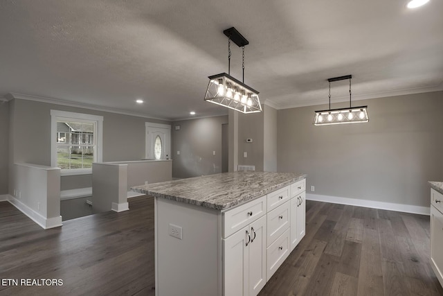 kitchen featuring crown molding, hanging light fixtures, light stone counters, white cabinets, and a kitchen island