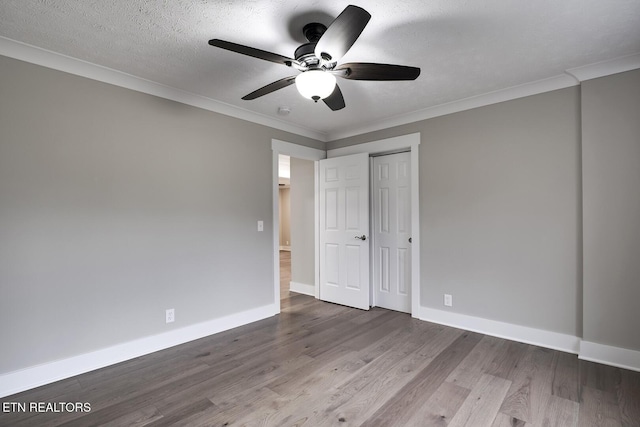 unfurnished bedroom with a textured ceiling, ornamental molding, a closet, ceiling fan, and hardwood / wood-style floors