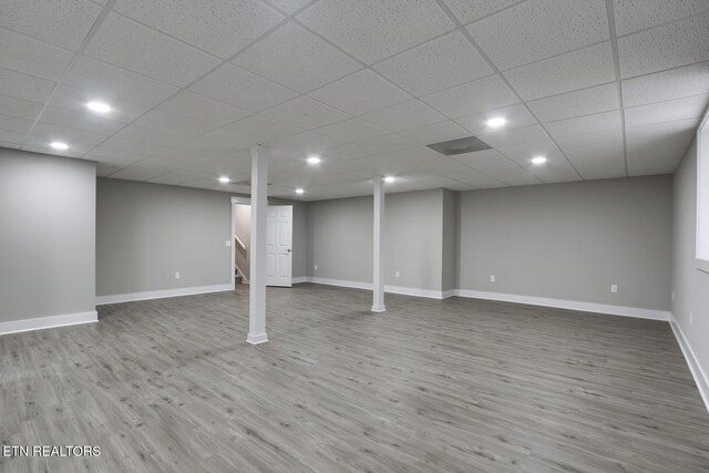 basement featuring hardwood / wood-style flooring and a paneled ceiling