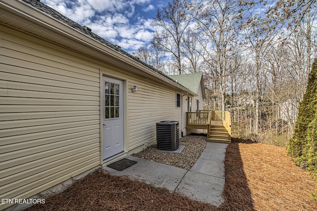 doorway to property featuring cooling unit and a wooden deck