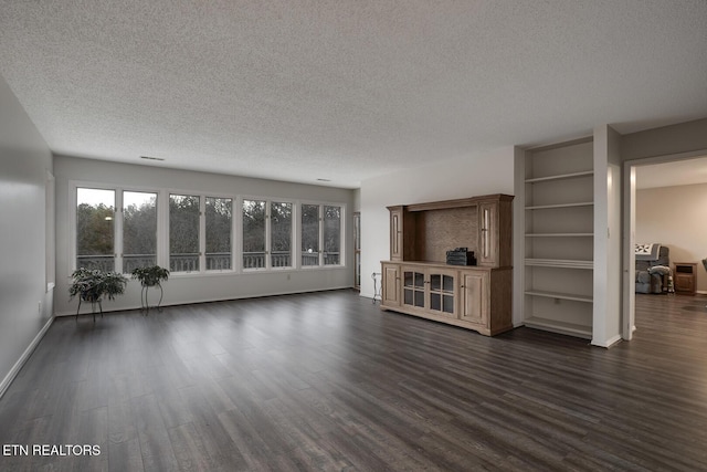 unfurnished living room with dark hardwood / wood-style flooring and a textured ceiling