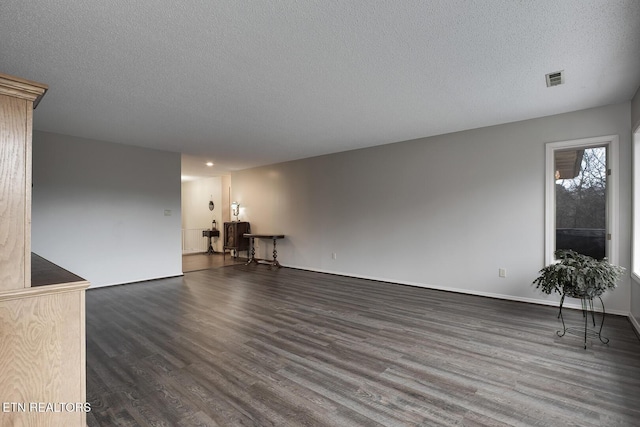 unfurnished living room featuring a textured ceiling and dark hardwood / wood-style flooring