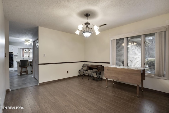 dining area with dark hardwood / wood-style flooring, ceiling fan with notable chandelier, and a textured ceiling