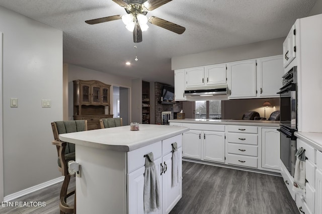 kitchen featuring dark hardwood / wood-style floors, white cabinetry, a kitchen bar, a center island, and kitchen peninsula