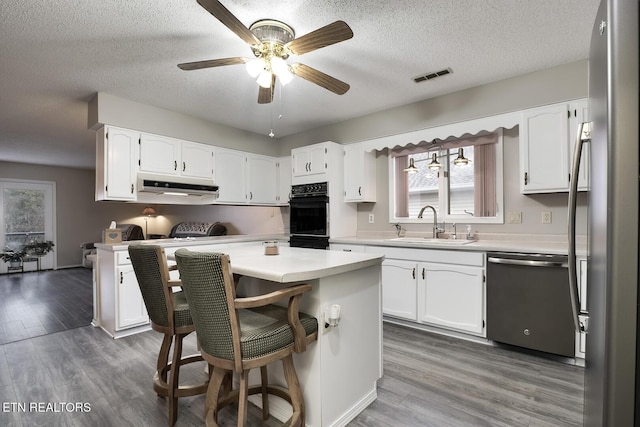 kitchen featuring sink, a kitchen bar, white cabinets, and appliances with stainless steel finishes