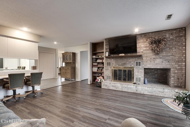 living room featuring built in features, dark hardwood / wood-style floors, a textured ceiling, and a fireplace