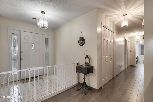 entrance foyer with hardwood / wood-style flooring, a chandelier, and a textured ceiling