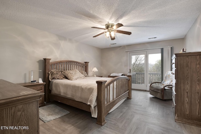 bedroom with a textured ceiling, access to outside, dark parquet floors, and ceiling fan