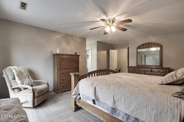 bedroom featuring ceiling fan, light parquet flooring, and a textured ceiling