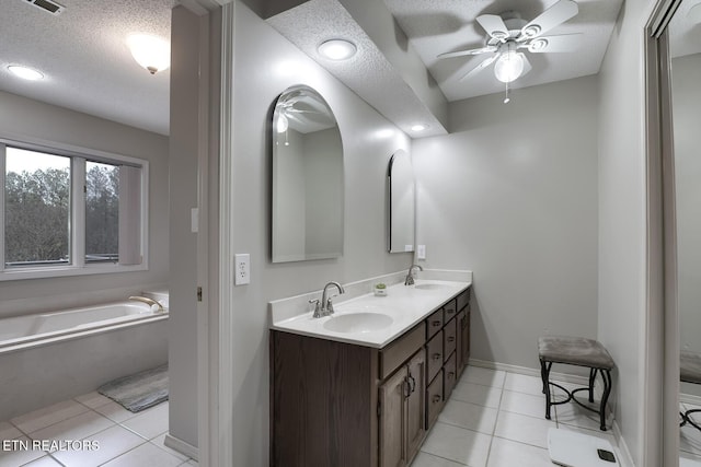 bathroom featuring a bathing tub, vanity, ceiling fan, tile patterned floors, and a textured ceiling