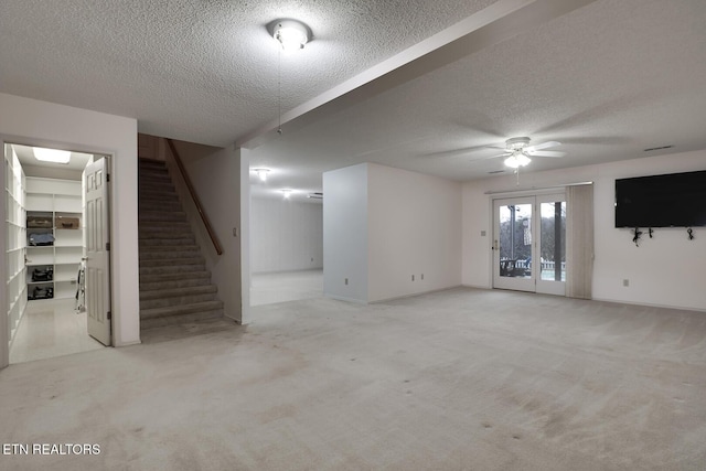 interior space with french doors, light colored carpet, ceiling fan, and a textured ceiling