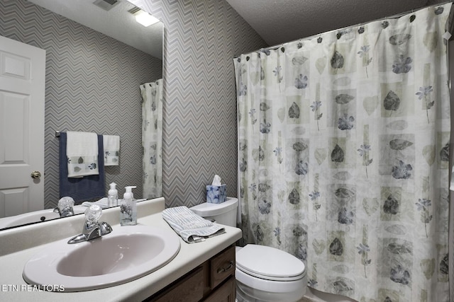 bathroom with walk in shower, vanity, toilet, and a textured ceiling