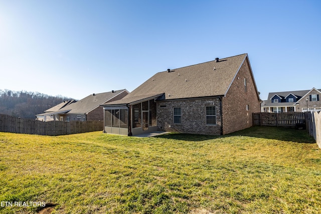 back of property with a sunroom and a lawn