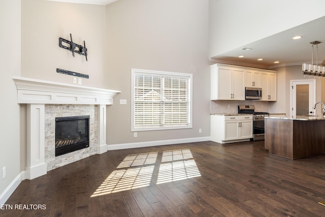 kitchen with dark wood-type flooring, appliances with stainless steel finishes, white cabinetry, backsplash, and light stone counters