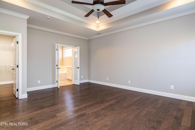 empty room with crown molding, dark wood-type flooring, ceiling fan, and a tray ceiling