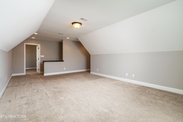 additional living space featuring vaulted ceiling and light colored carpet