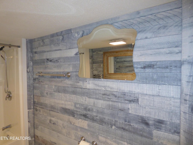 room details with wood walls, a textured ceiling, and a shower