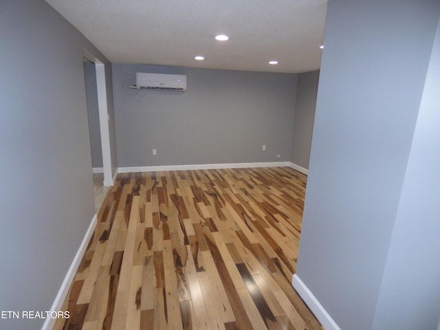 basement with hardwood / wood-style floors and a wall unit AC