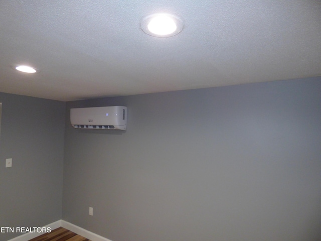 basement with hardwood / wood-style floors, a textured ceiling, and a wall mounted AC