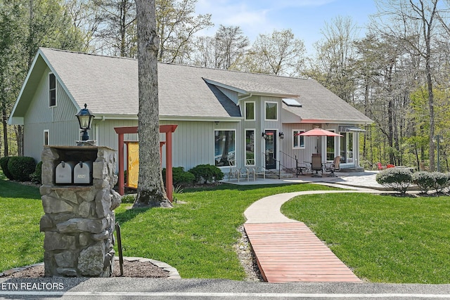 view of front of property with a patio area, a front yard, and roof with shingles