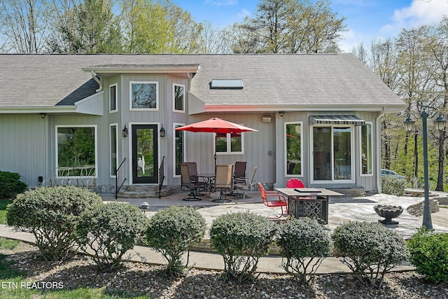 rear view of house featuring a patio and roof with shingles