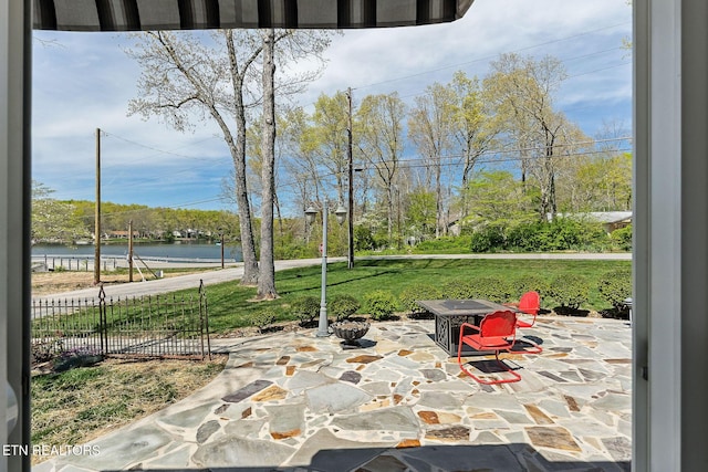 view of patio featuring a water view and fence