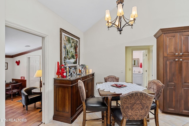 dining room with light wood-style floors, an inviting chandelier, ornamental molding, and vaulted ceiling