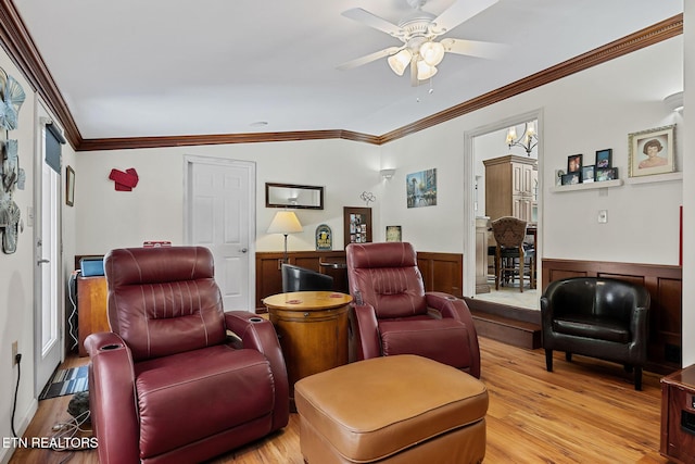 living area with a ceiling fan, light wood-style floors, ornamental molding, and wainscoting