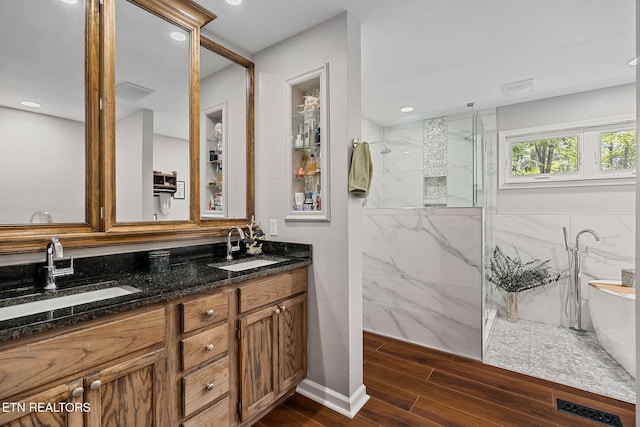 full bath with a marble finish shower, visible vents, wood finished floors, and a sink