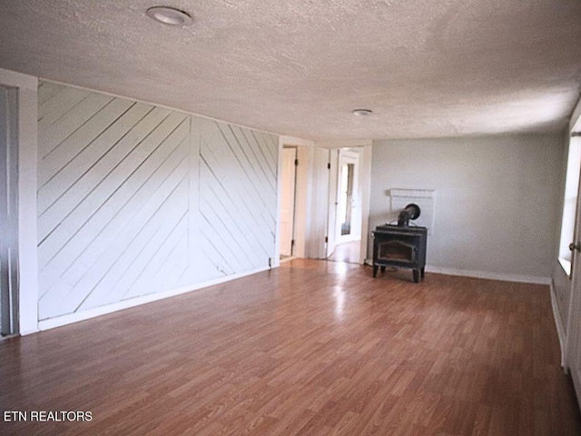 unfurnished living room with dark hardwood / wood-style floors, a textured ceiling, and a wood stove