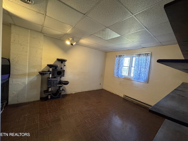 workout room with a baseboard radiator, dark parquet flooring, and a drop ceiling