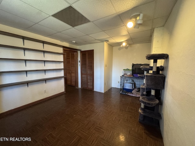 basement featuring a paneled ceiling and dark parquet floors