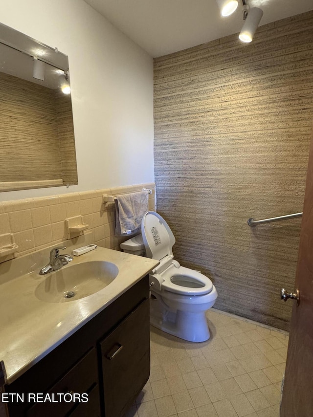 bathroom with tile walls, vanity, and toilet