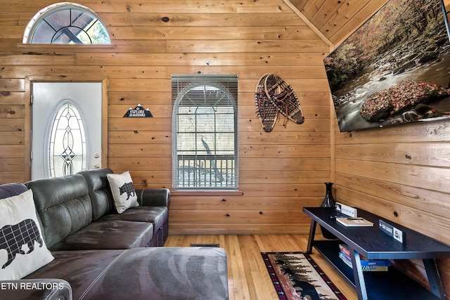 living room with vaulted ceiling, a wealth of natural light, hardwood / wood-style floors, and wood walls