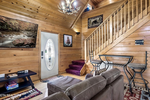 living room with wood ceiling, light hardwood / wood-style flooring, an inviting chandelier, wooden walls, and vaulted ceiling