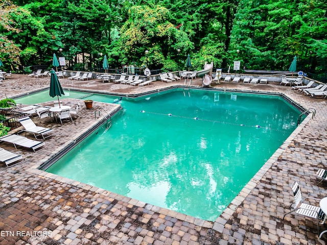 view of swimming pool featuring a water slide and a patio area