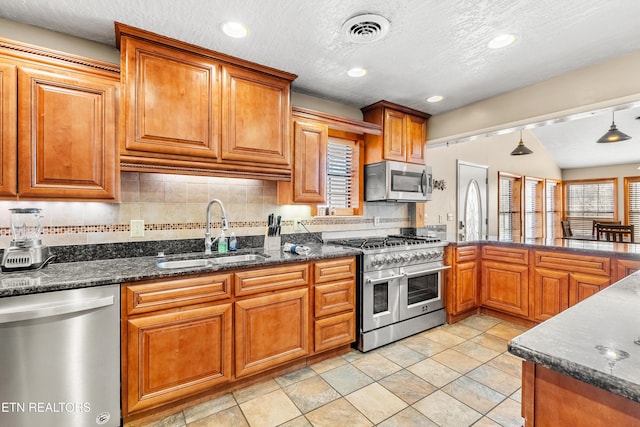 kitchen with stainless steel appliances, plenty of natural light, sink, and decorative light fixtures