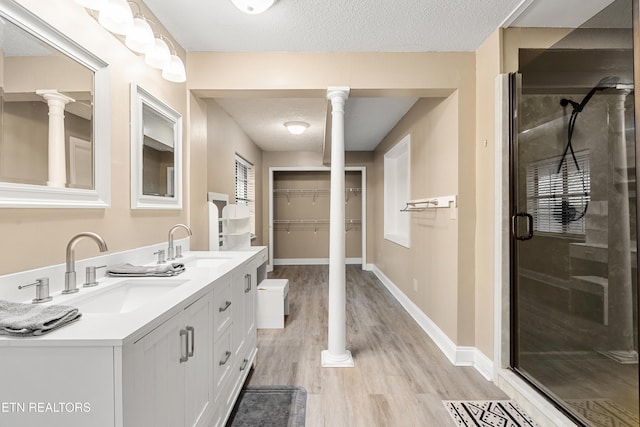 bathroom featuring an enclosed shower, ornate columns, wood-type flooring, a textured ceiling, and vanity