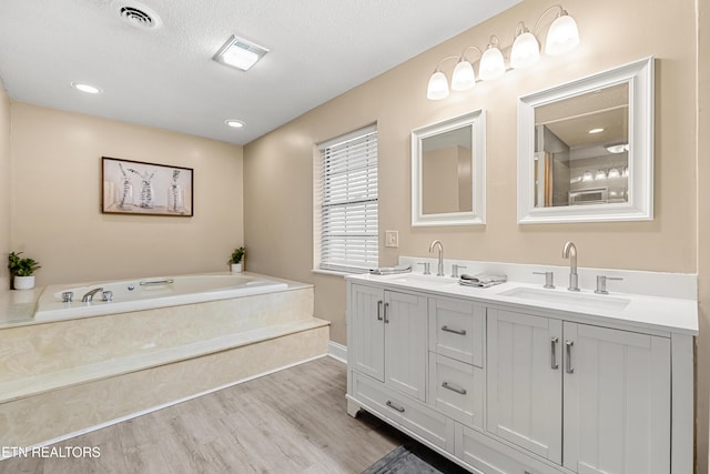 bathroom featuring vanity, a bathing tub, hardwood / wood-style floors, and a textured ceiling