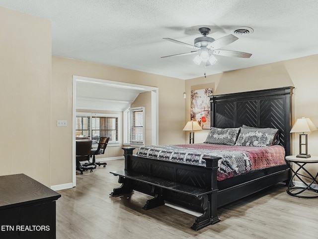 bedroom with ceiling fan, light hardwood / wood-style flooring, and a textured ceiling