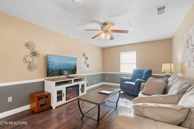 living room featuring ceiling fan, dark hardwood / wood-style floors, and a textured ceiling