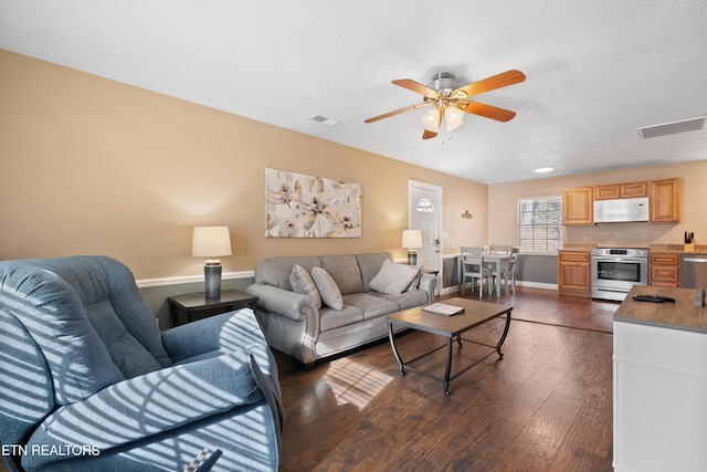 living room with ceiling fan, a textured ceiling, and dark hardwood / wood-style flooring